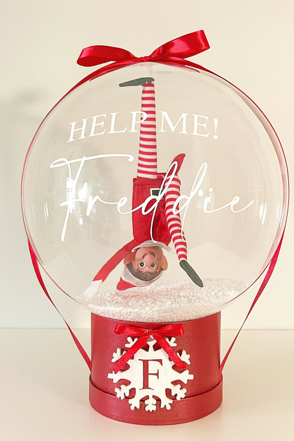 Clear snow globe balloon showing upside-down elf toy and festive message — personalized Christmas surprise